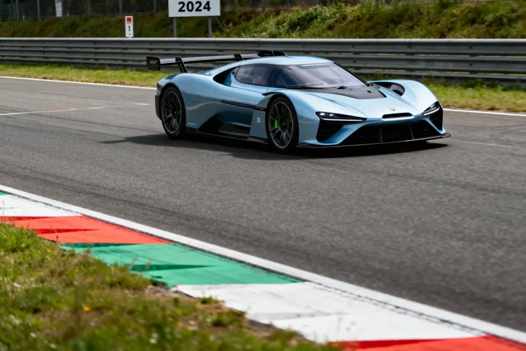 Voiture de sport bleue sur circuit, avec signe "2024" en arrière-plan.