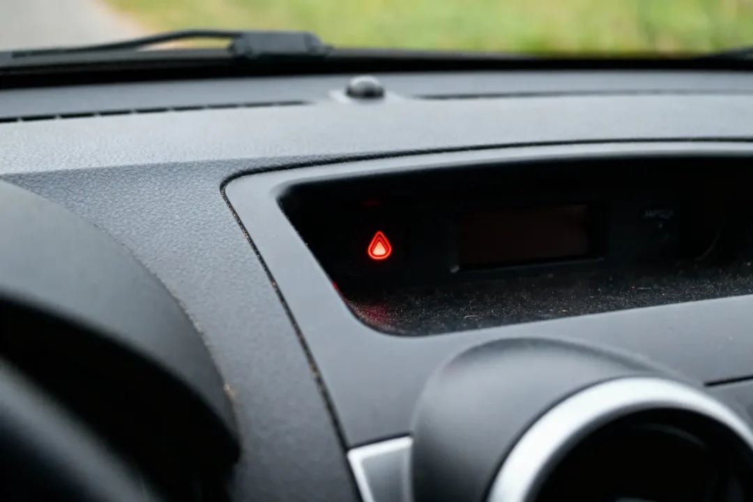 Tableau de bord de voiture avec voyant lumineux rouge allumé, intérieur en plastique noir.