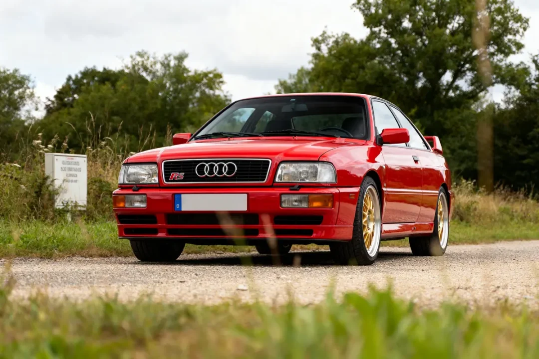Voiture rouge Audi RS2 Avant stationnée sur chemin avec fond de nature verte
