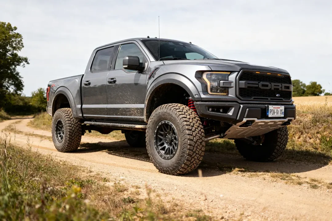 Ford Raptor 4 door gris sur chemin tout-terrain poussiéreux en campagne verte