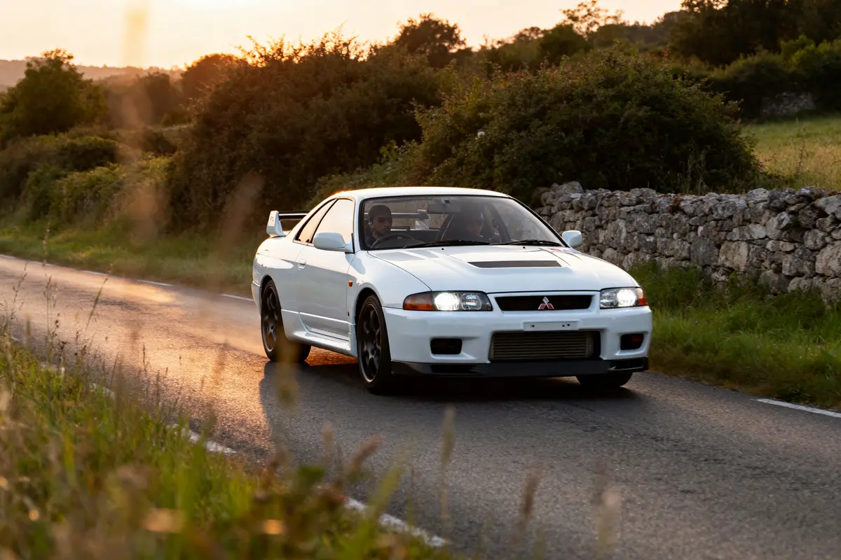 Voiture blanche Mitsubishi GTR roulant sur route de campagne au coucher du soleil