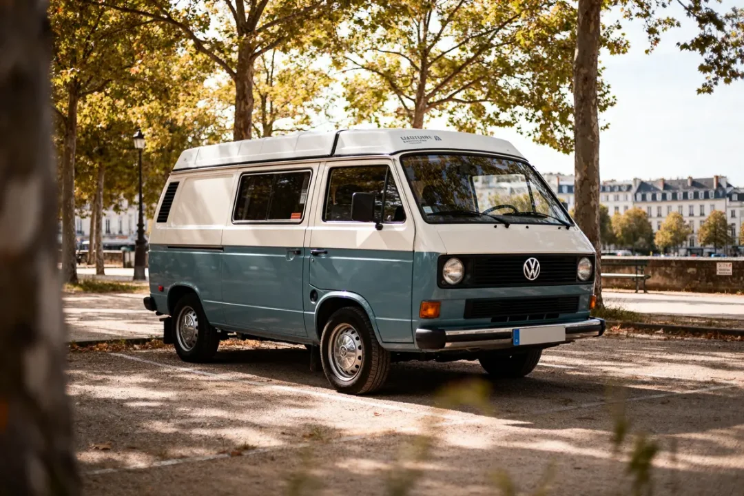 Volkswagen van vintage stationné sous les arbres près de bâtiments en arrière-plan urbain