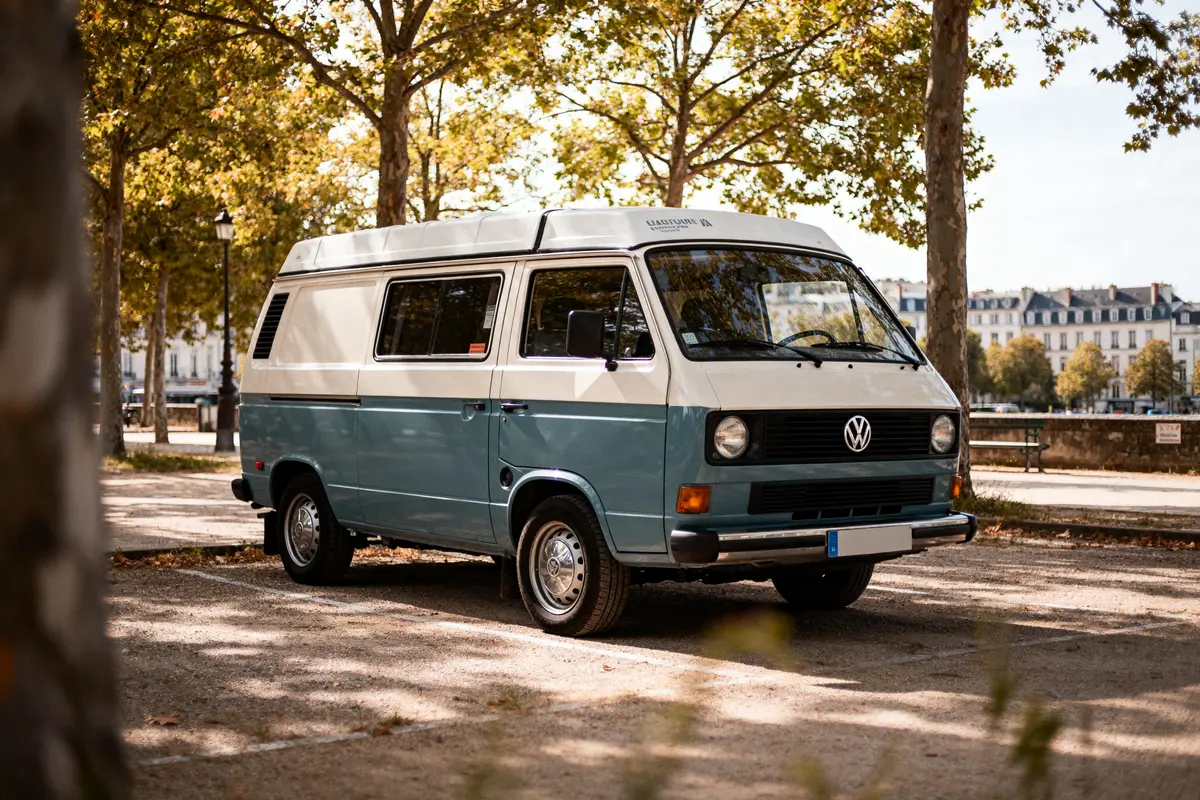 Volkswagen van vintage stationné sous les arbres près de bâtiments en arrière-plan urbain