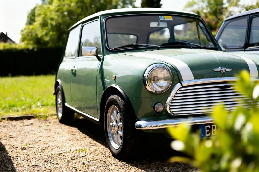 Voiture classique austin Mini verte garée sur une allée ensoleillée devant un jardin