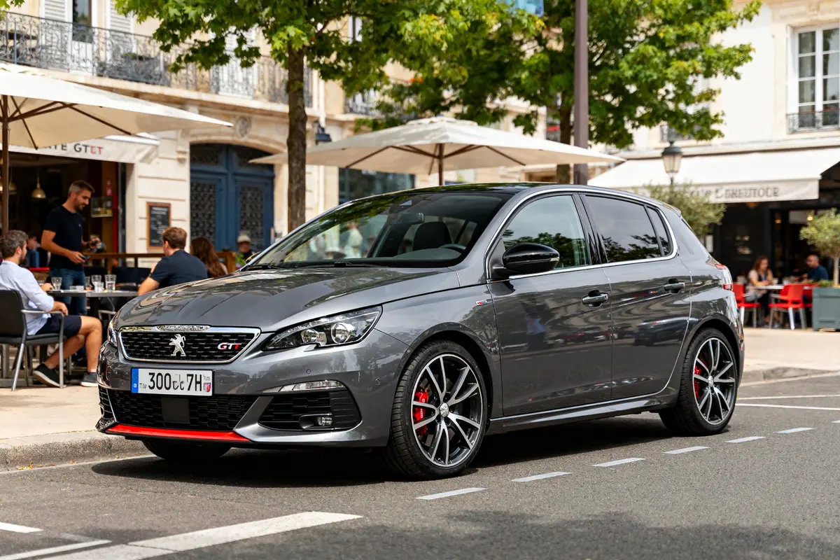 Voiture grise 308 GTI Automatic stationnée devant café en ville, environnement urbain animé.