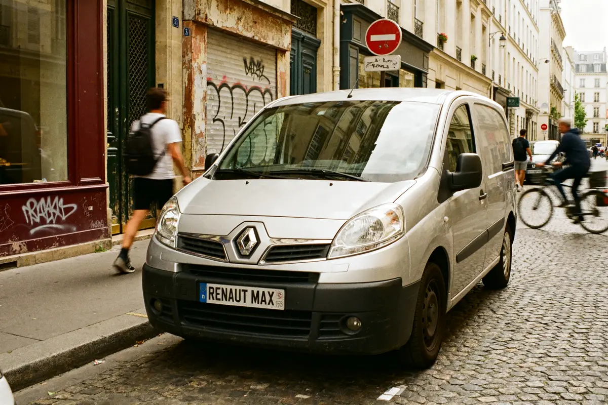 Fourgon Renault Maxity argenté stationné dans une rue pavée urbaine animée