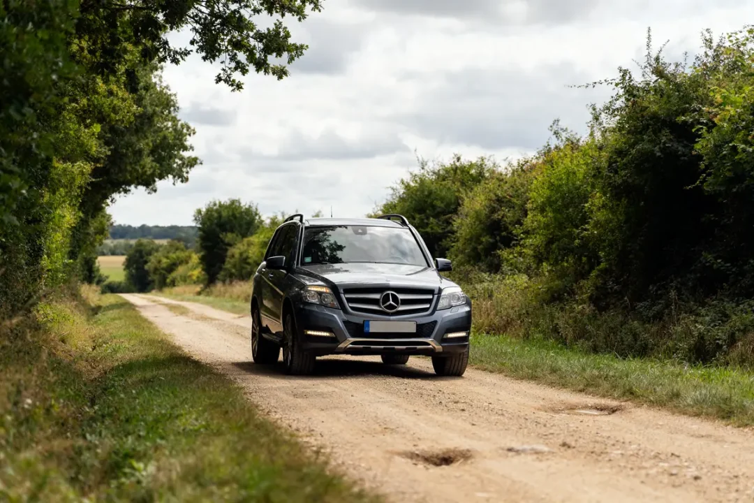 SUV Mercedes GLK roulant sur un chemin de campagne entouré de verdure abondante