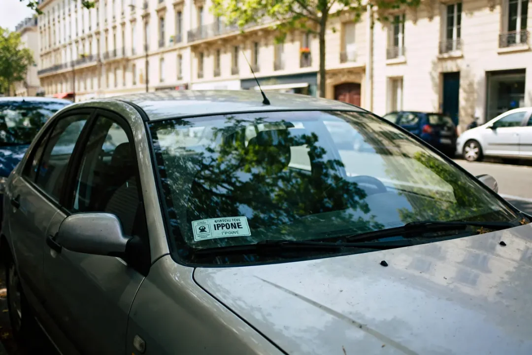 Voiture grise stationnée rue avec contrôle technique périmé depuis 1 mois visible sur pare-brise