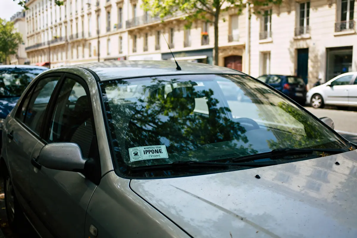 Voiture grise stationnée rue avec contrôle technique périmé depuis 1 mois visible sur pare-brise
