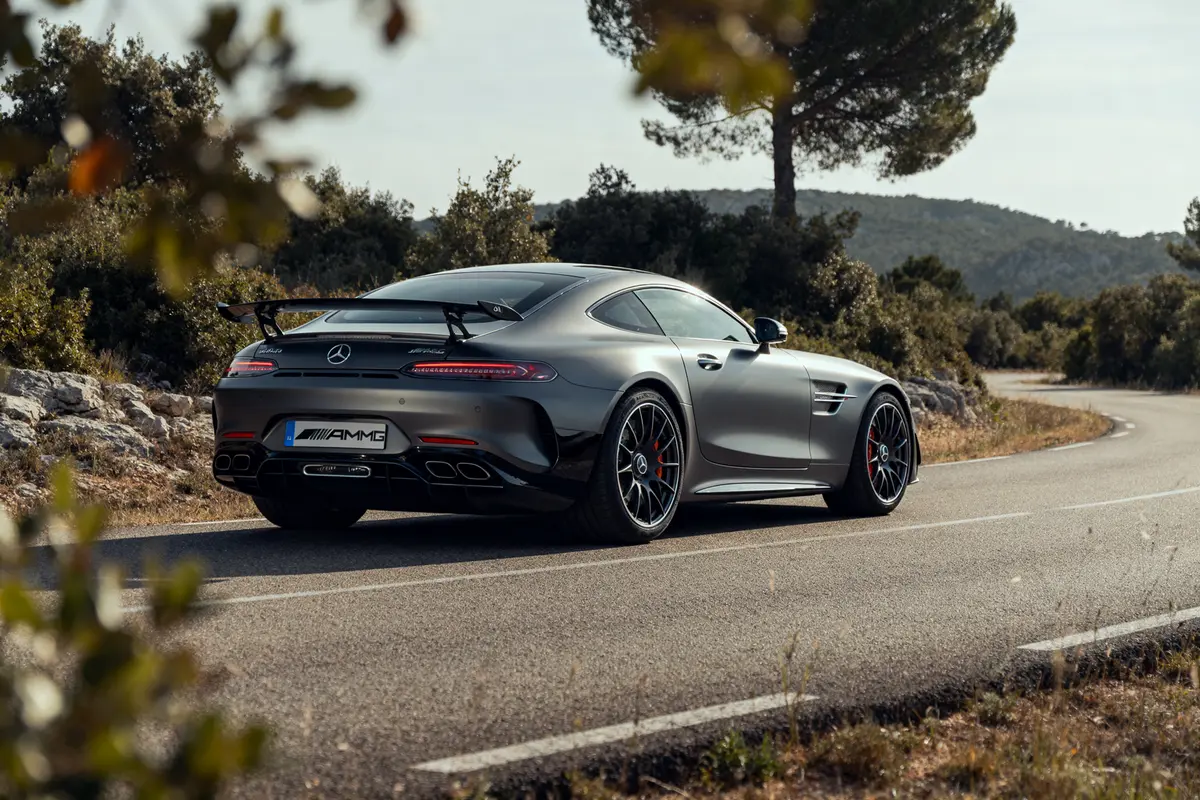 Mercedes-AMG Gran Turismo grise sur une route sinueuse en pleine nature verdoyante