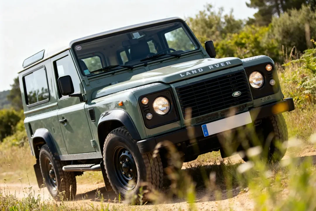 Land Rover Defender 300 TDI sur chemin terreux en pleine nature verdoyante