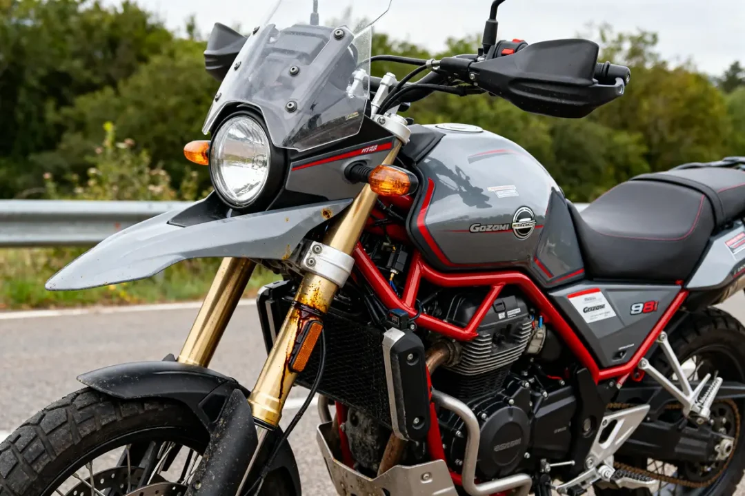 Moto Guzzi V85 TT sur route, vue de côté, possible problème mécanique sur la fourche avant